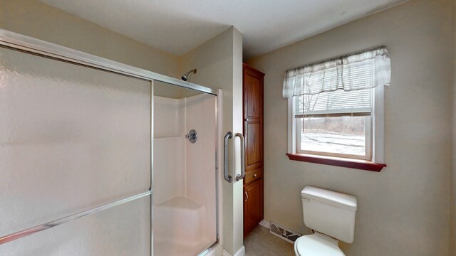 bathroom with an enclosed shower, tile patterned flooring, and toilet