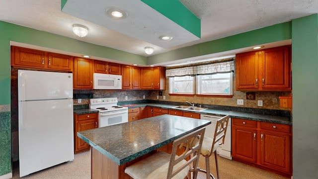 kitchen with sink, white appliances, a breakfast bar area, a center island, and decorative backsplash