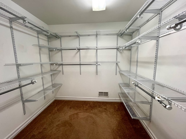 walk in closet featuring dark colored carpet