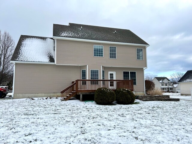 snow covered back of property featuring a deck