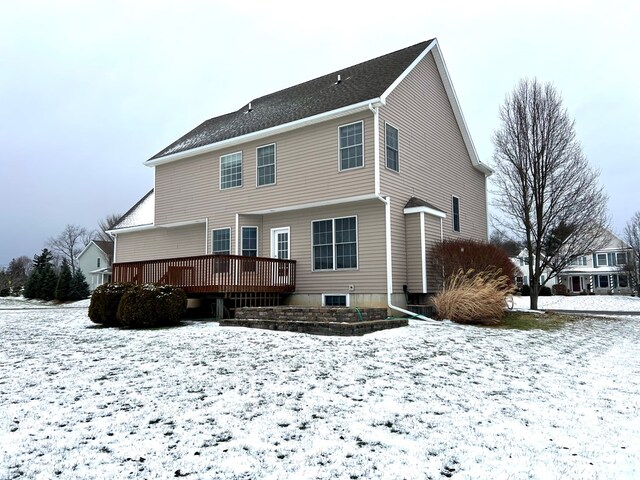 snow covered back of property with a wooden deck