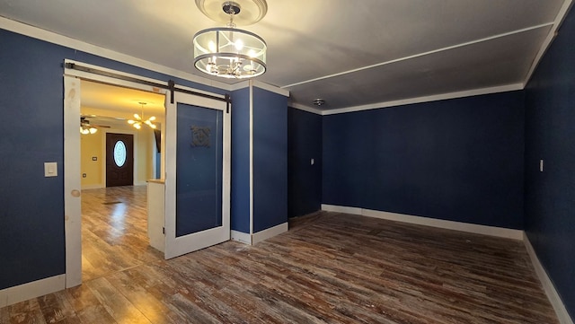 unfurnished room featuring dark wood-type flooring, ornamental molding, a barn door, and ceiling fan with notable chandelier