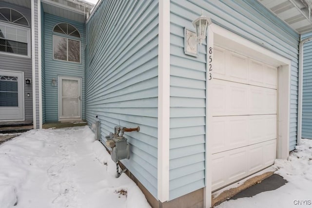 snow covered property with a garage