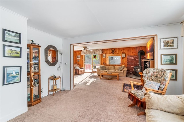 living room with ornamental molding, carpet floors, a wood stove, and wood walls