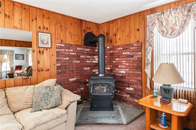 carpeted living room featuring wood walls and a wood stove