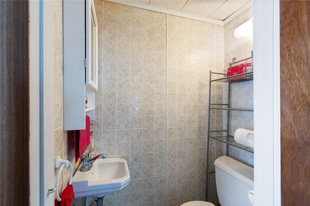 bathroom featuring sink, tile walls, and toilet