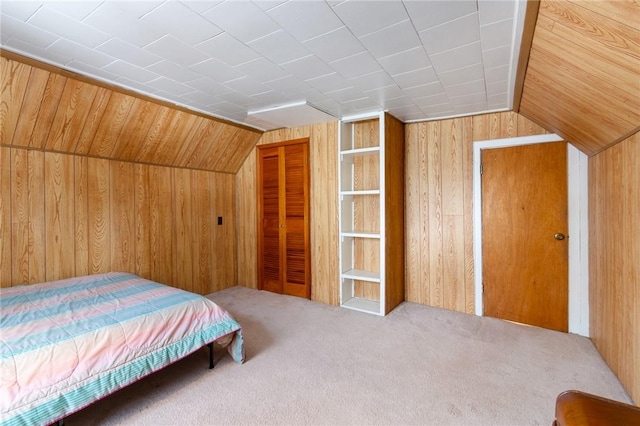 bedroom with lofted ceiling, carpet, a closet, and wood walls