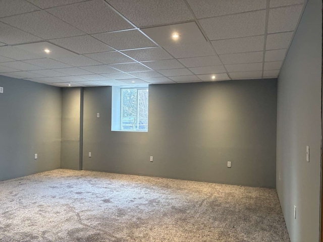 basement with a paneled ceiling and carpet flooring