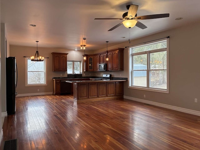 kitchen featuring pendant lighting, sink, black appliances, dark hardwood / wood-style flooring, and ceiling fan with notable chandelier