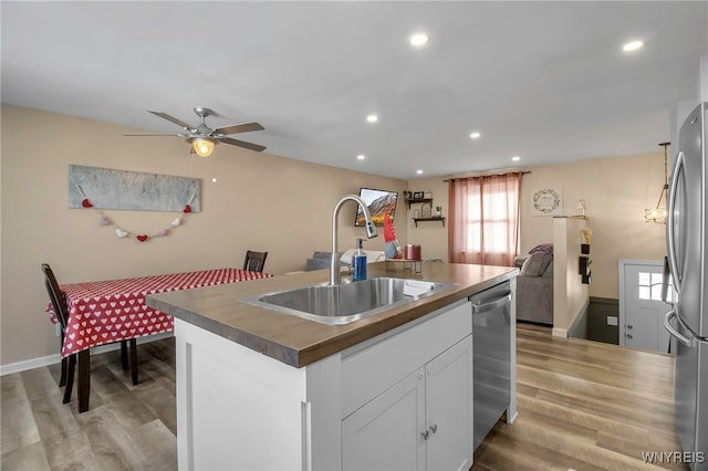 kitchen with sink, appliances with stainless steel finishes, light hardwood / wood-style floors, an island with sink, and white cabinets