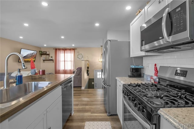 kitchen with white cabinetry, appliances with stainless steel finishes, sink, and backsplash