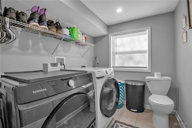 laundry area featuring washing machine and clothes dryer and light tile patterned floors