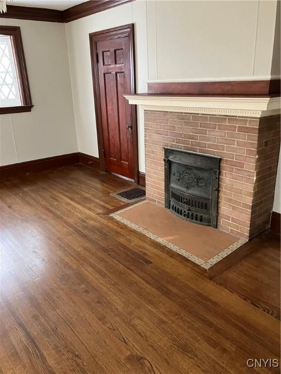 unfurnished living room with crown molding, dark hardwood / wood-style flooring, and a brick fireplace