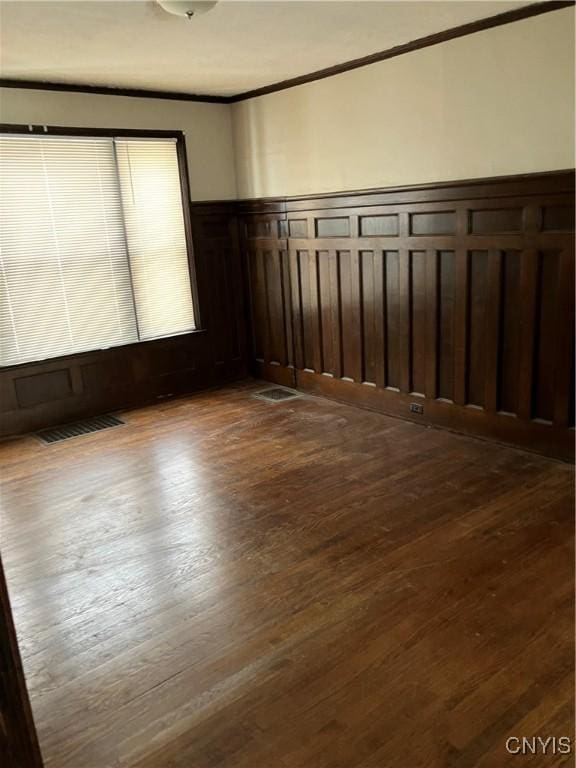 spare room featuring crown molding and dark hardwood / wood-style floors