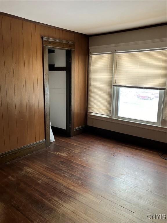 empty room with dark hardwood / wood-style floors and wooden walls