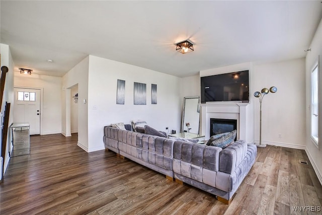 living room featuring a wealth of natural light and dark wood-type flooring