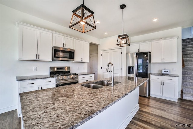 kitchen featuring white cabinetry, stainless steel appliances, decorative light fixtures, and sink