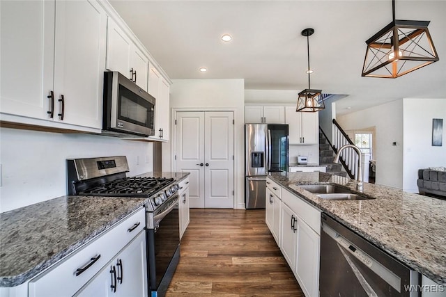 kitchen featuring stainless steel appliances, a kitchen island with sink, white cabinets, and decorative light fixtures