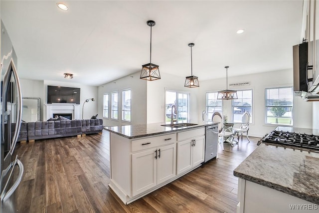 kitchen featuring sink, white cabinetry, stainless steel appliances, a center island with sink, and decorative light fixtures