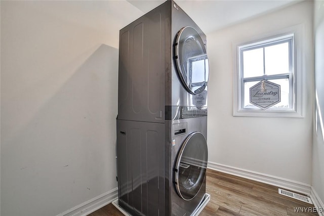 laundry area featuring stacked washing maching and dryer and hardwood / wood-style floors