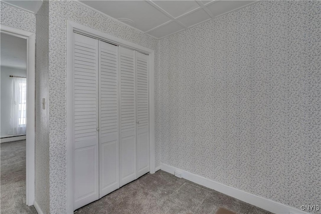 unfurnished bedroom featuring a baseboard radiator, carpet flooring, and a closet