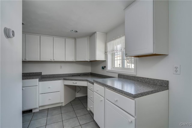 kitchen with white cabinetry, built in desk, and light tile patterned floors