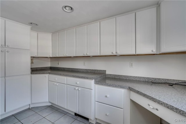 kitchen with white cabinetry, light tile patterned flooring, and built in desk