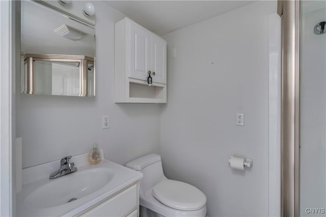 bathroom with vanity, toilet, and a shower with door