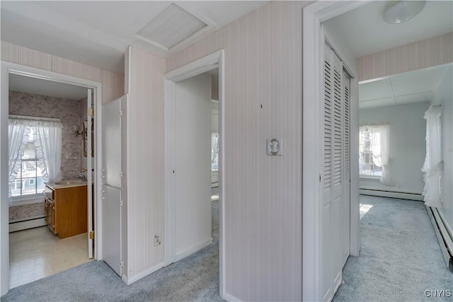 hallway featuring a baseboard radiator, a wealth of natural light, and light carpet