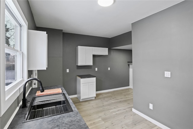 kitchen with light wood-type flooring, sink, and white cabinets