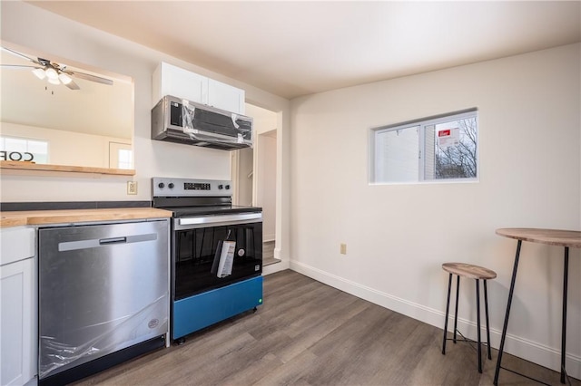 kitchen with white cabinetry, butcher block countertops, dark hardwood / wood-style floors, and appliances with stainless steel finishes