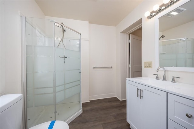 bathroom featuring vanity, hardwood / wood-style floors, a shower with shower door, and toilet