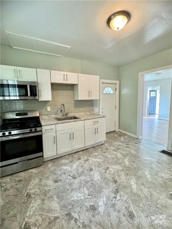 kitchen featuring appliances with stainless steel finishes, sink, white cabinets, and decorative backsplash