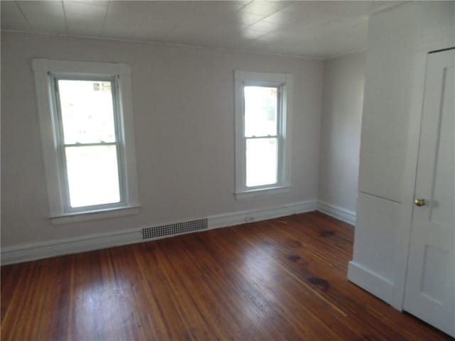 spare room featuring a wealth of natural light and dark hardwood / wood-style flooring