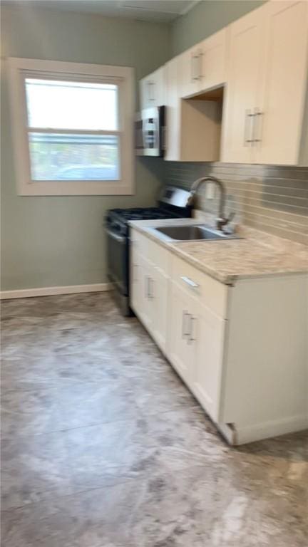 kitchen with gas range, sink, and white cabinets