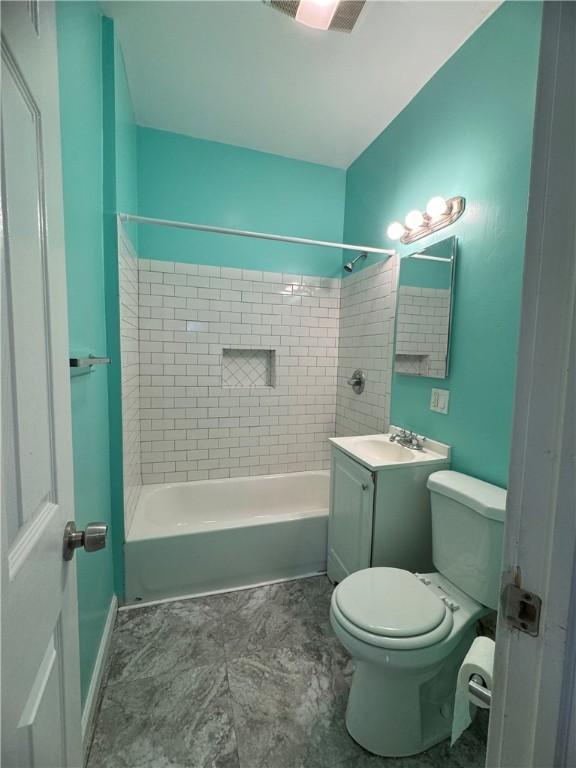 full bathroom with vanity, tiled shower / bath combo, and toilet