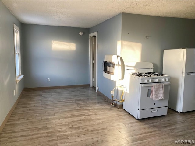 kitchen with heating unit, white appliances, light hardwood / wood-style flooring, and a textured ceiling