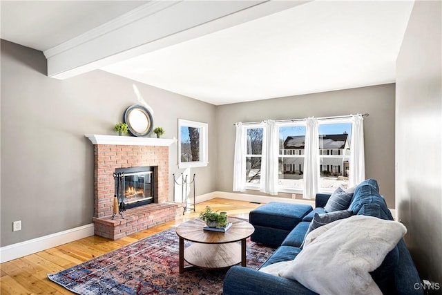 living room with a brick fireplace, beam ceiling, and wood-type flooring