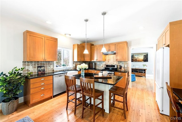 kitchen with pendant lighting, light hardwood / wood-style flooring, a breakfast bar, stainless steel appliances, and a center island