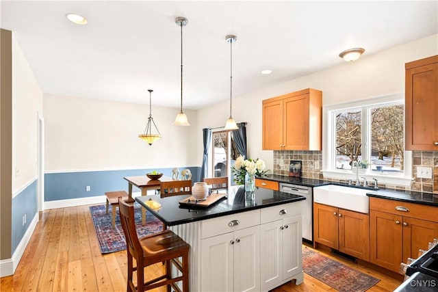 kitchen featuring tasteful backsplash, a breakfast bar area, hanging light fixtures, a center island, and stainless steel dishwasher