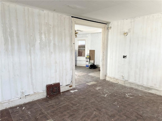 unfurnished room featuring wooden walls