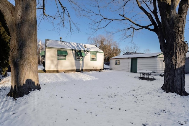 snow covered back of property with an outbuilding