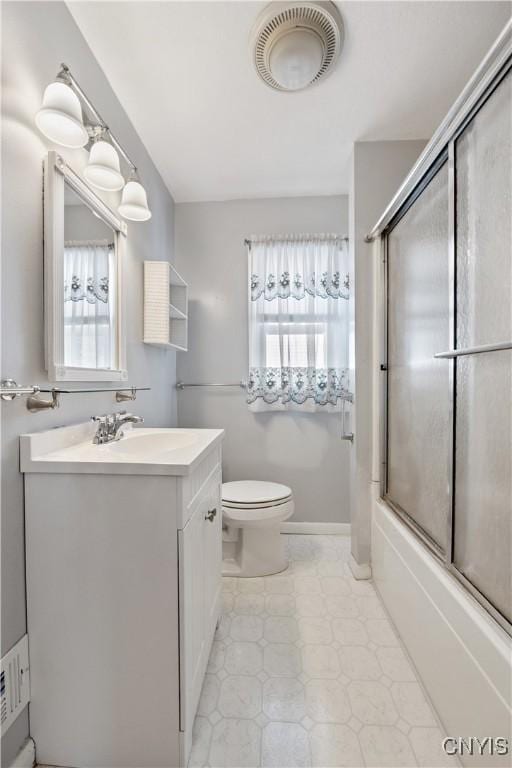 full bathroom with vanity, toilet, combined bath / shower with glass door, and a wealth of natural light