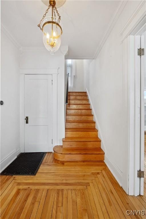 stairs featuring crown molding and an inviting chandelier