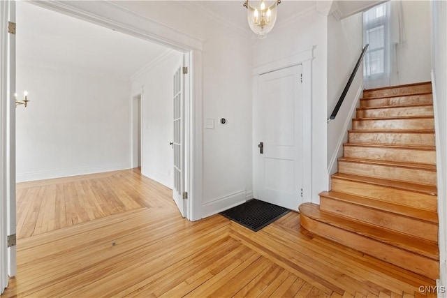 entrance foyer featuring crown molding, wood-type flooring, and a notable chandelier