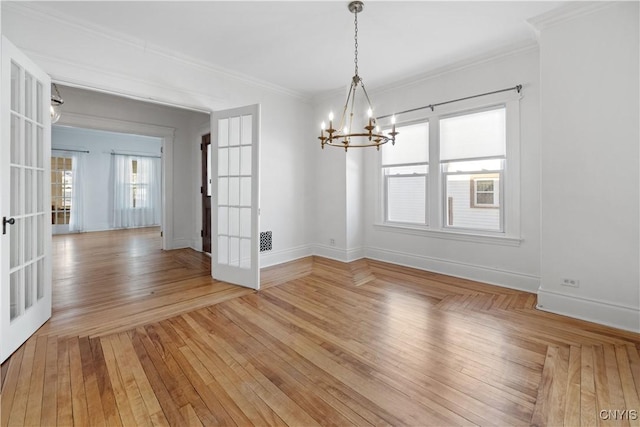 unfurnished dining area featuring a notable chandelier, ornamental molding, french doors, and light wood-type flooring