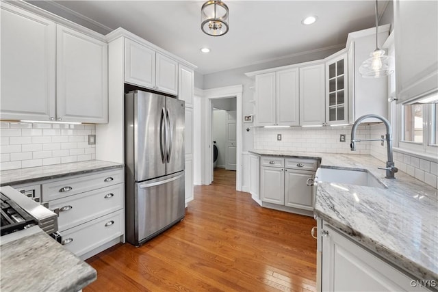 kitchen featuring decorative light fixtures, white cabinetry, sink, stainless steel fridge, and hardwood / wood-style flooring