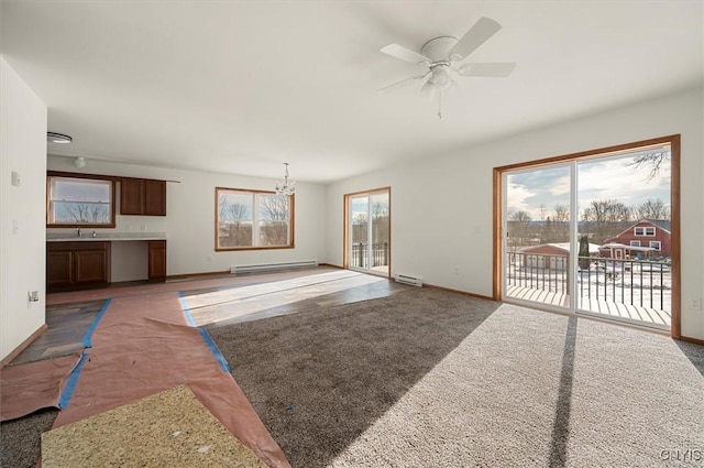 living room with sink, ceiling fan with notable chandelier, baseboard heating, and dark carpet