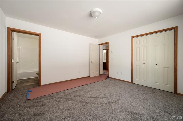 unfurnished bedroom featuring ensuite bathroom, a closet, and dark colored carpet