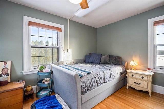 bedroom with multiple windows, hardwood / wood-style floors, and ceiling fan